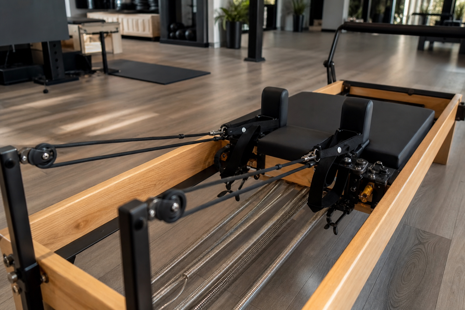 A clean, high-angle interior shot of a Pilates Reformer machine in a studio, emphasizing the springs