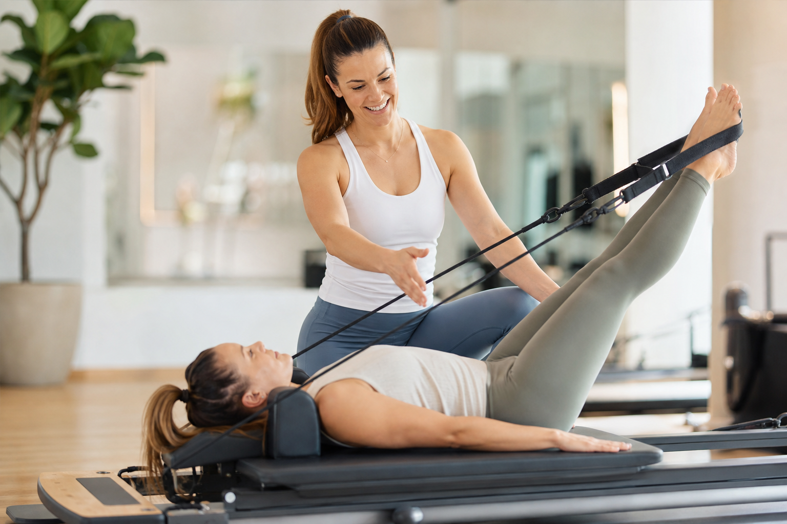 A friendly female pilates instructor demonstrating a reformer exercise, smiling, encouraging, wearin