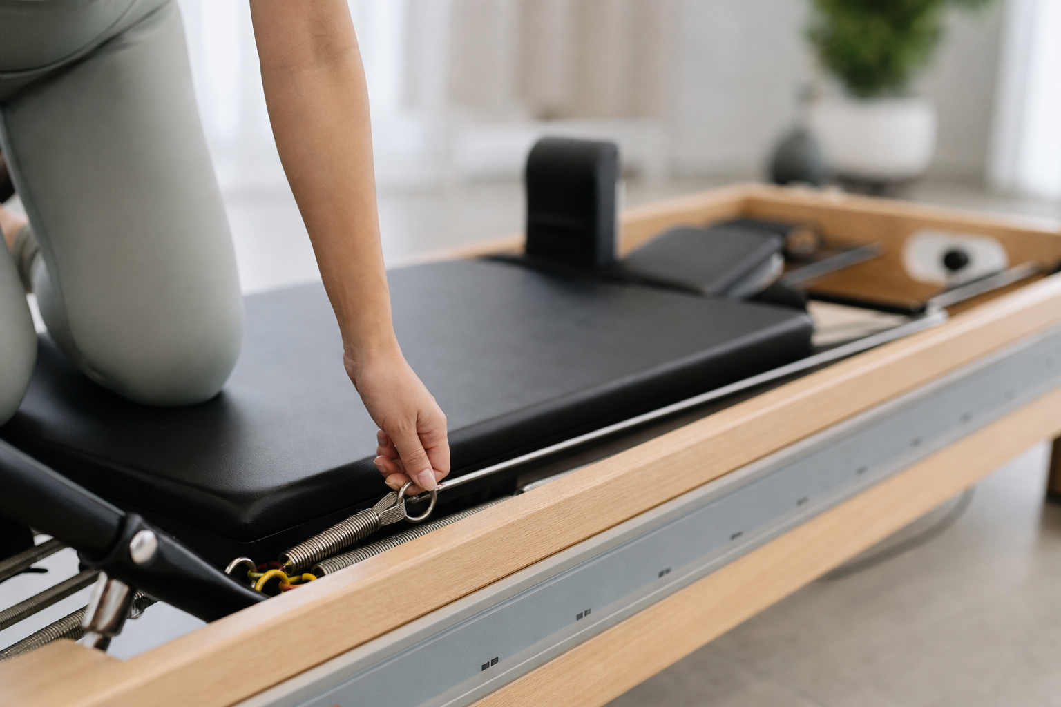 A close-up shot of a person using a pilates reformer machine, emphasizing the spring mechanism and t
