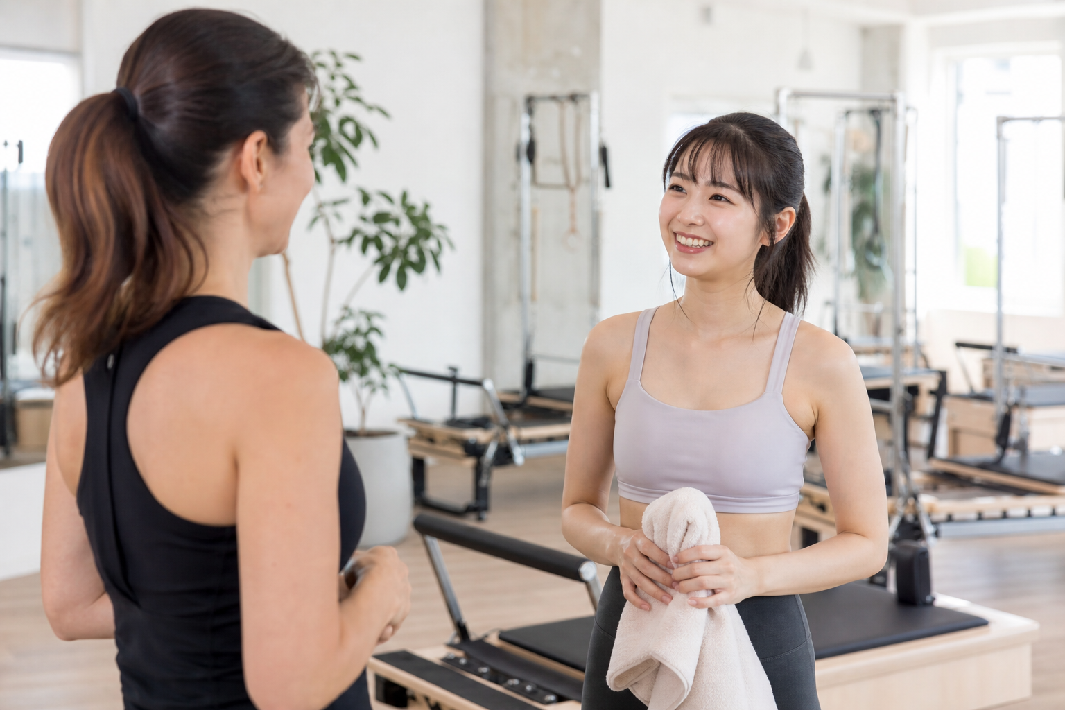 A friendly illustration of a person smiling while talking to an instructor in a bright pilates studi