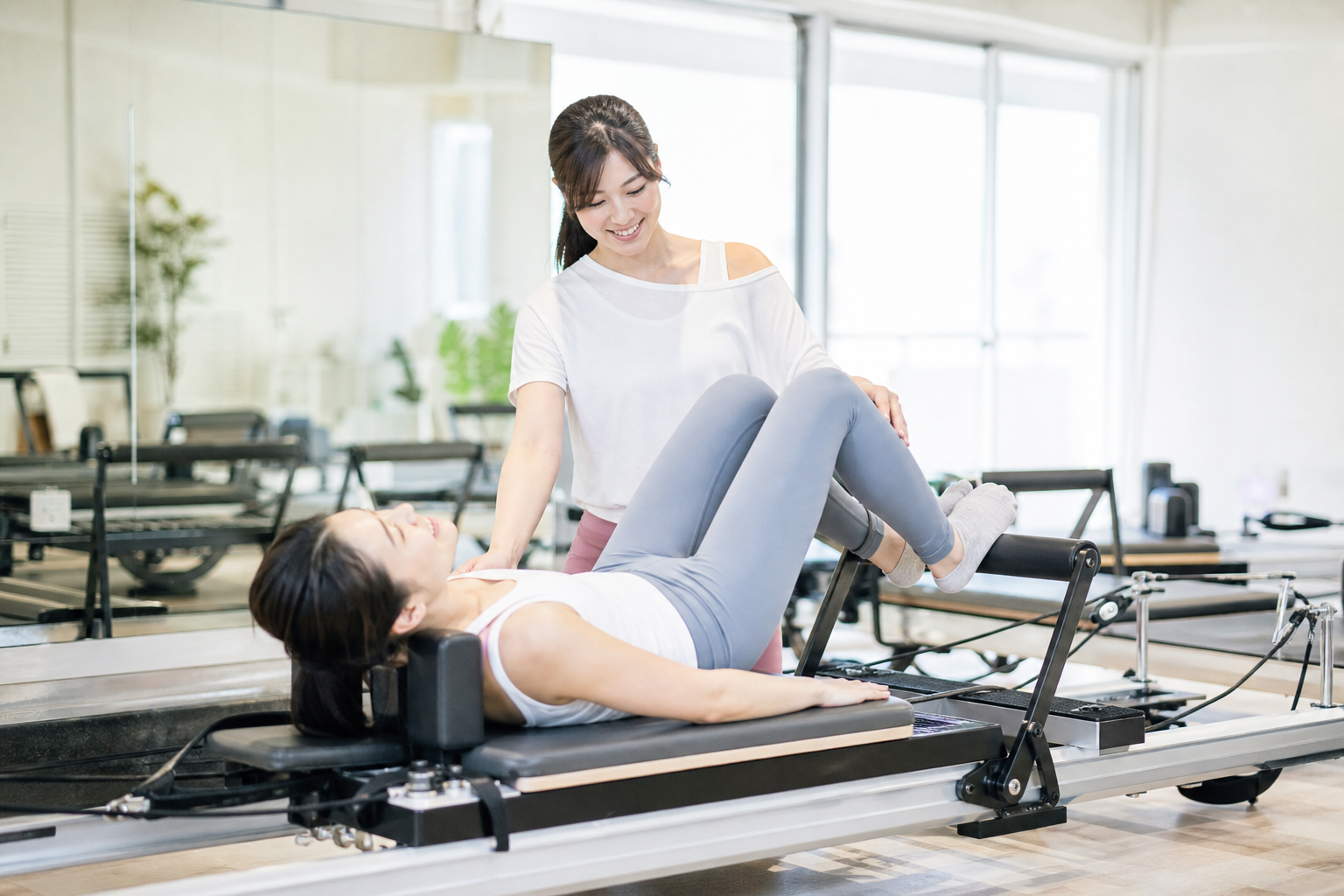 マシンピラティスを体験する女性の様子。リフォーマーを使用し、インストラクターが優しく指導している場面。明るく開放的なスタジオで、健康的に運動を楽しんでいる様子。高品質な写真スタイル。