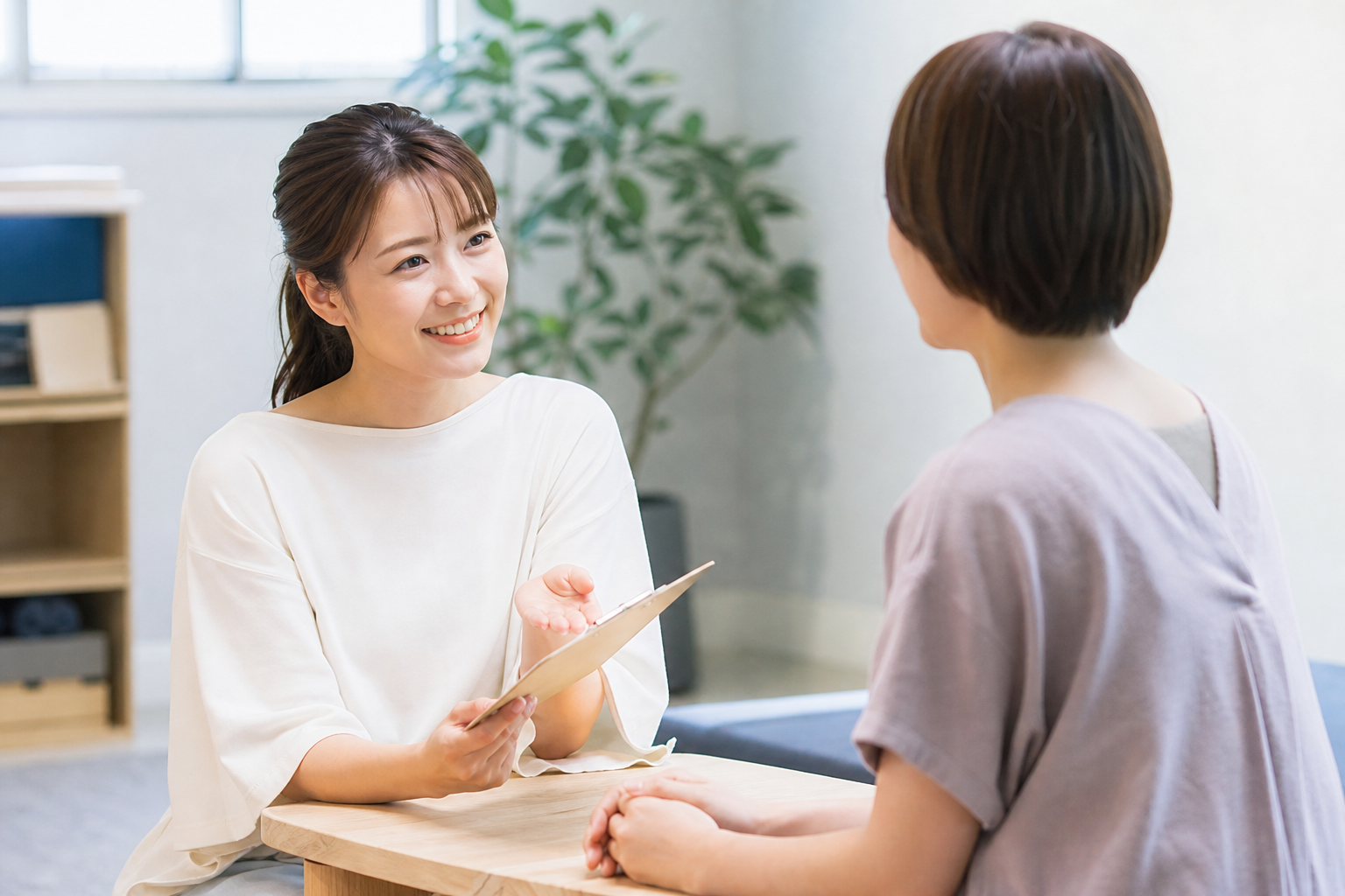 インストラクターが親身になって相談に乗っているカウンセリングの様子をイメージした画像。心地よいスタジオの雰囲気の中で、女性が笑顔でアドバイスを受けている、安心感のある対面風景。