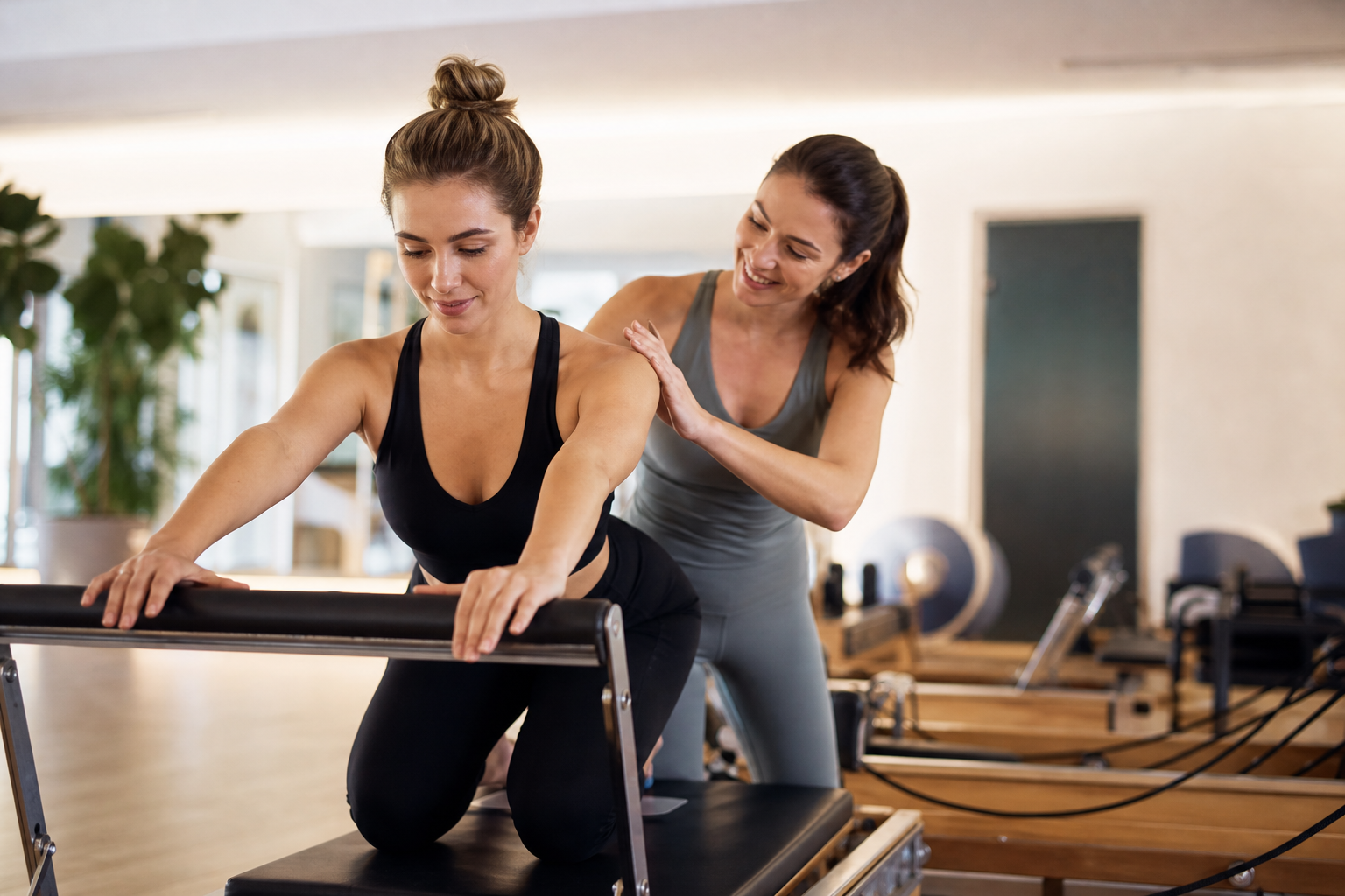 A warm and inviting image of a female instructor guiding a student on a Pilates reformer machine in